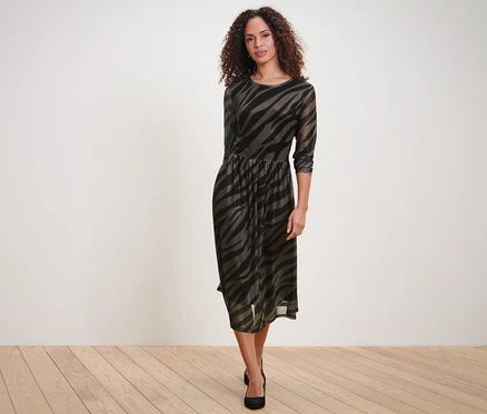 Frau posiert in einem bedruckten Mesh-Kleid.