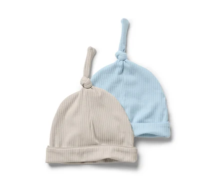 Zwei Baby-Jerseymützen, eine hellblau und eine beige, liegen nebeneinander.