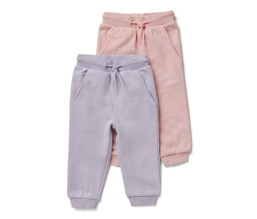Zwei Baby-Sweathosen: eine helllila und eine rosa mit weißen Punkten.