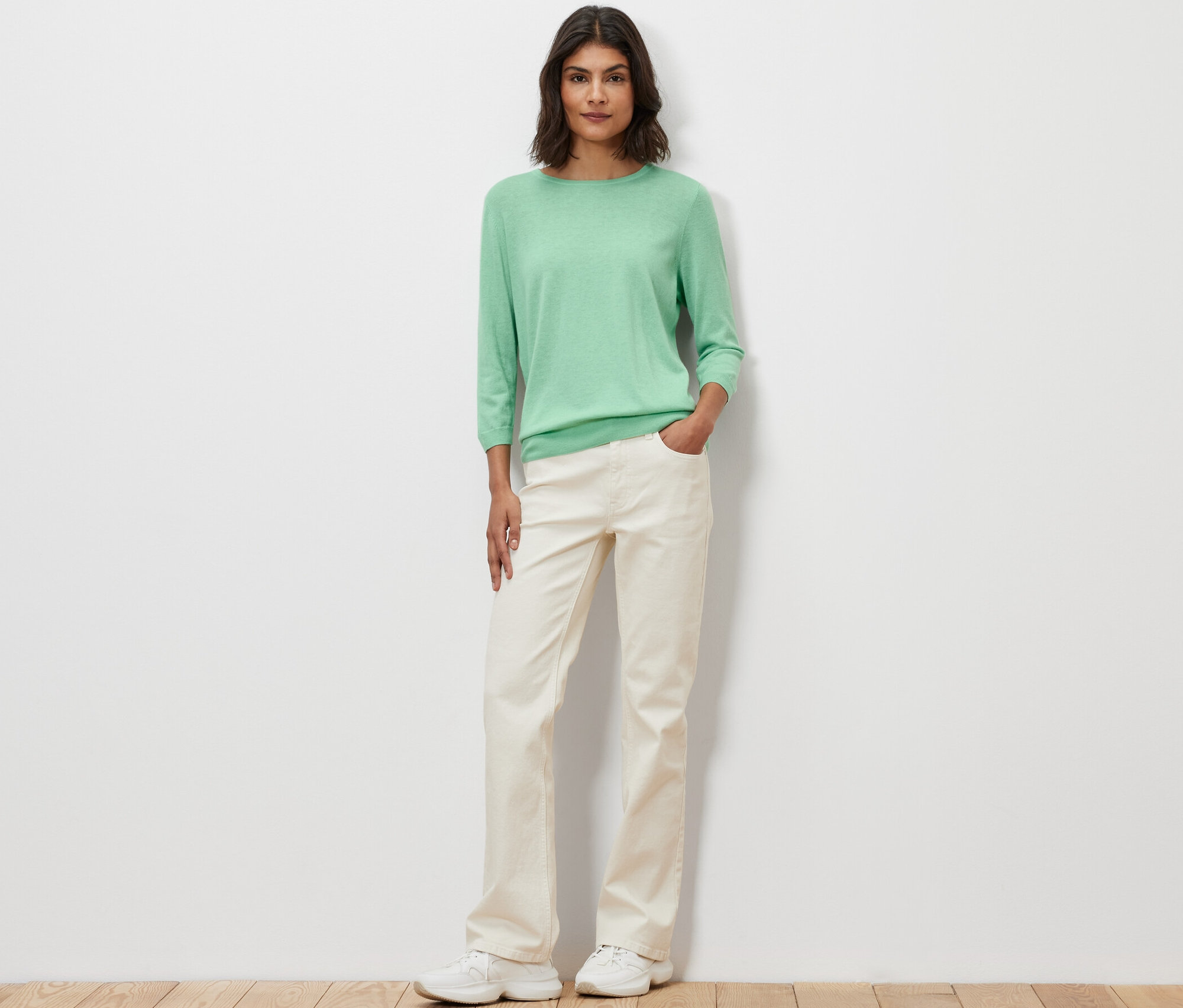 Eine Frau posiert und trägt einen hellgrünen Feinstrickpullover mit Seide.