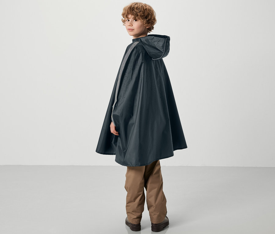 Ein Junge blickt über die Schulter und trägt einen blauen Kinder-Regenponcho.