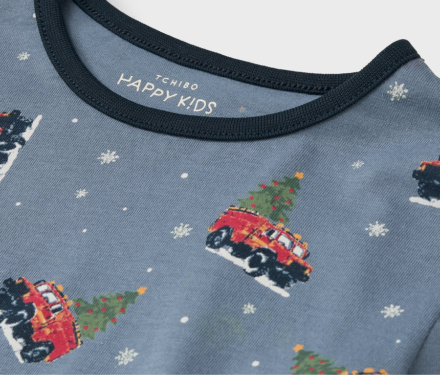 Detail eines blauen T-Shirts mit Aufdruck von Autos mit Weihnachtsbäumen und Schneeflocken.