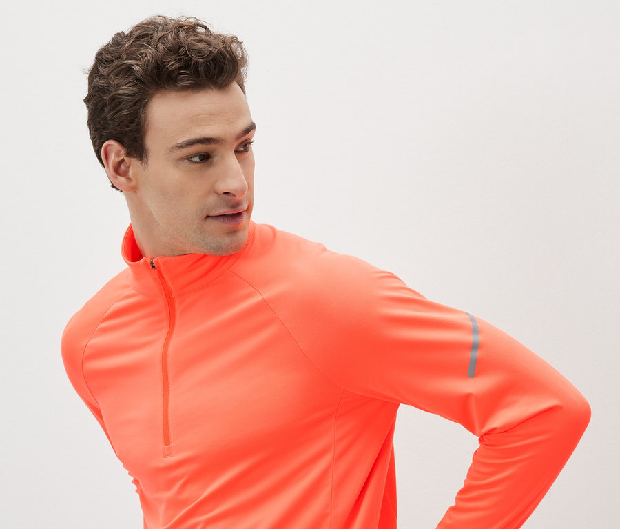 Mann in orangefarbenem Sport-Langarmshirt mit Reißverschluss.