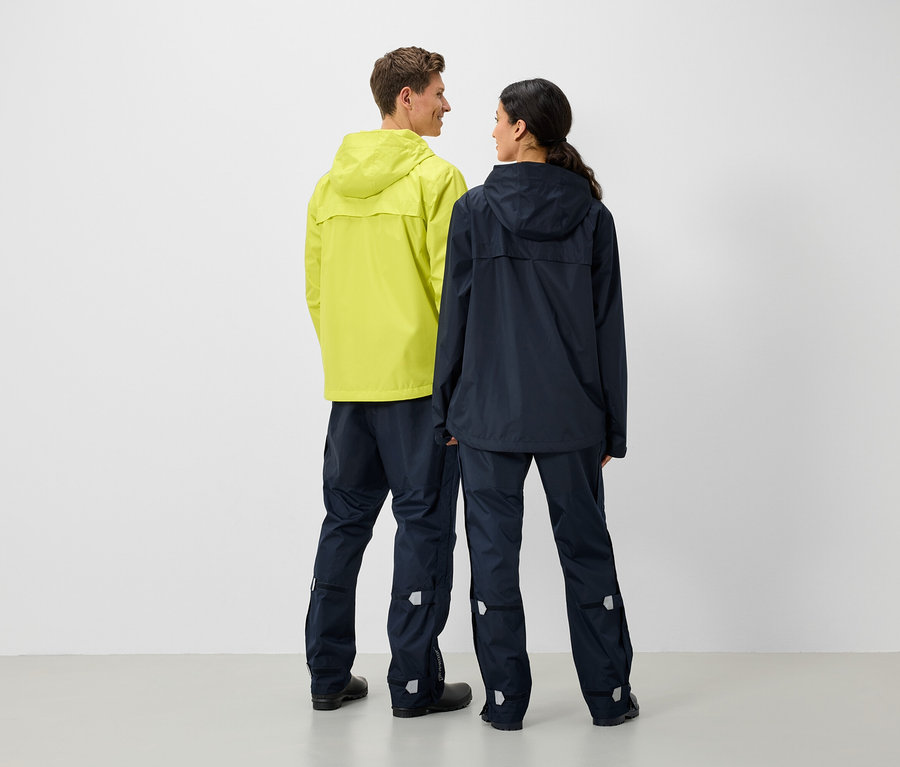 Ein Mann und eine Frau stehen Rücken an Rücken und tragen Regenjacken und -hosen.