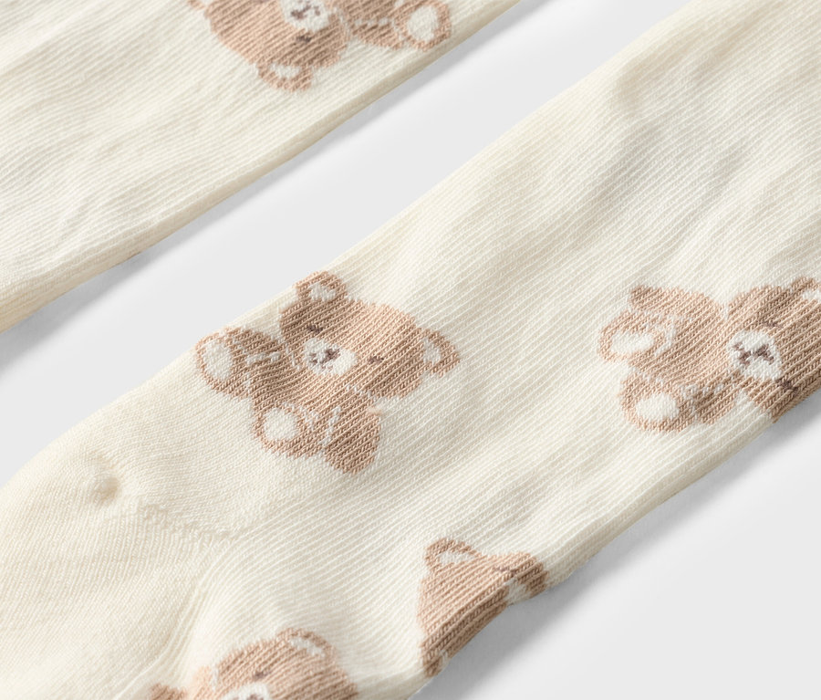 Nahaufnahme von zwei cremefarbenen Socken mit braunen Teddybären.