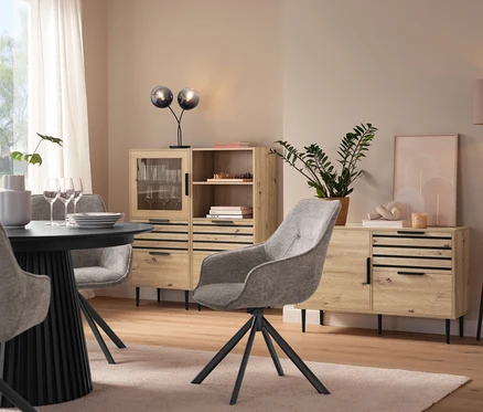 Esszimmer mit Esstisch, grauen Stühlen, einer Vitrine »BAAKEN« mit Glastür, einem Regal »BAAKEN« mit Schubladen und einem Sideboard mit Schubladen.