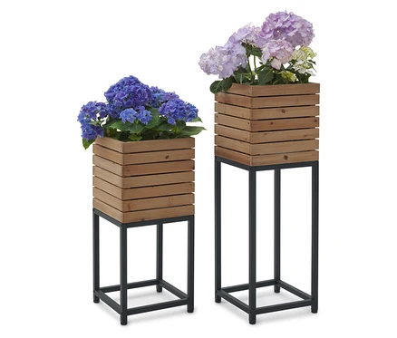 Zwei Blumenständer aus Holz mit blauen und lilafarbenen Hortensienblüten darauf.