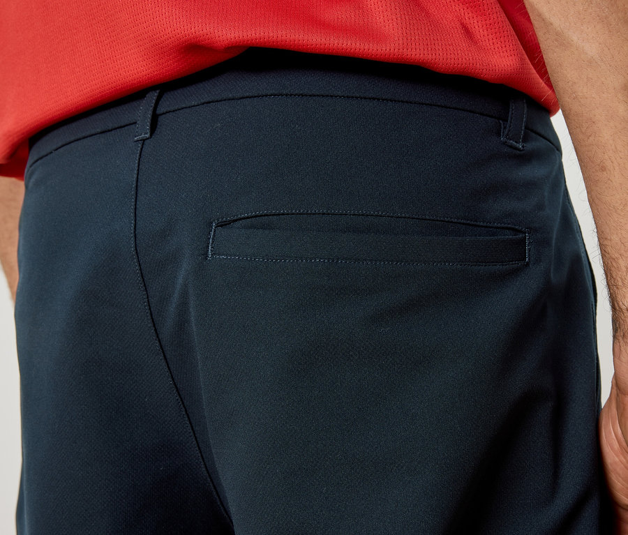 Nahaufnahme der Rückseite einer dunkelblauen Hose mit Gesäßtasche, getragen von einer Person in einem roten Oberteil.