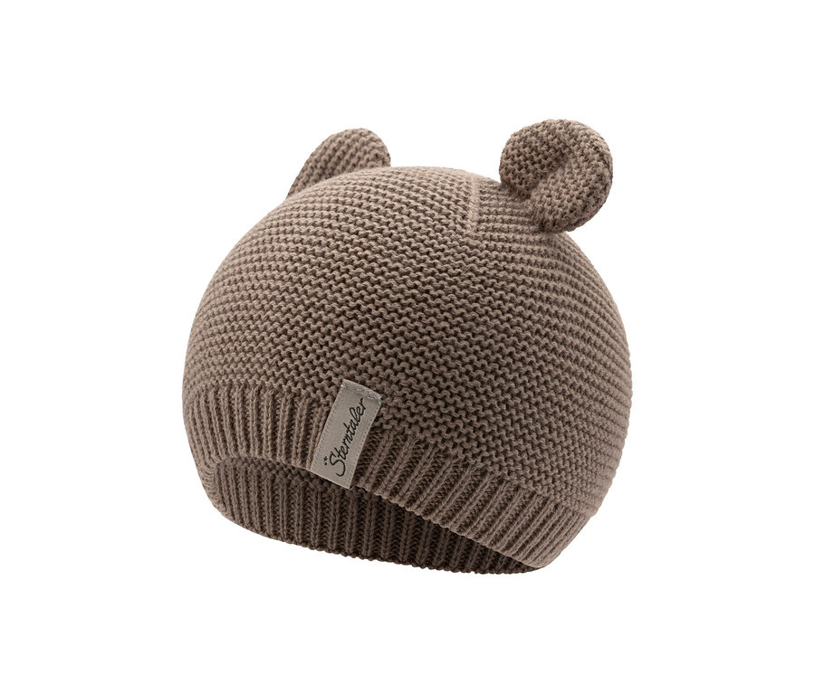 Eine hellbraune Strickmütze für Babys mit zwei kleinen, runden Ohren oben und einem 'Sterntaler'-Etikett an der Seite.