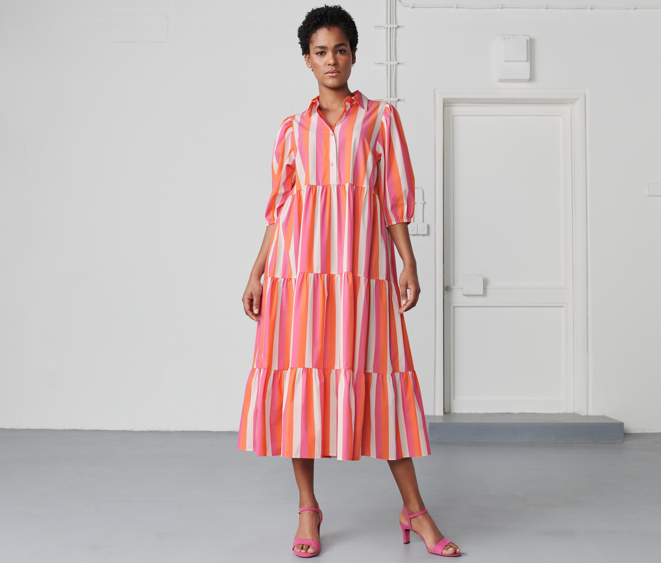 Frau posiert in einem gestreiften Webkleid.