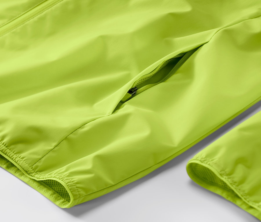 Detailaufnahme einer neonlimefarbenen Windprotection-Laufjacke mit Reißverschluss.
