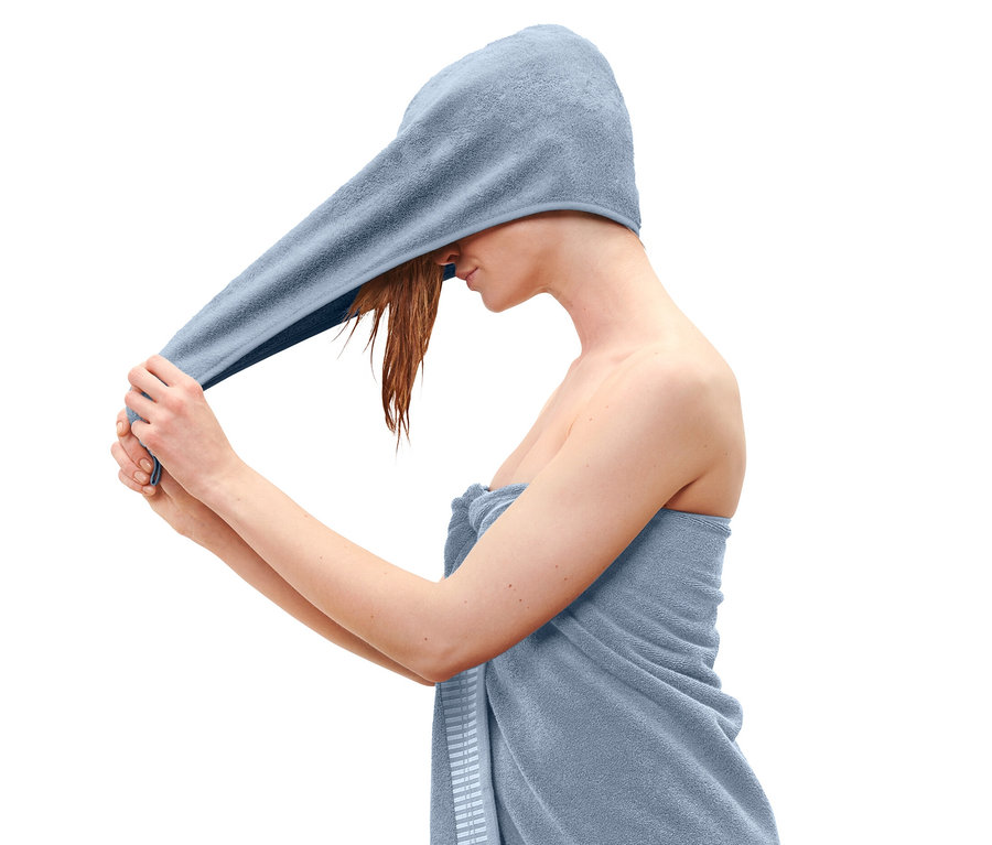 Frau legt ein hellblaues Turban-Handtuch auf ihren Kopf.