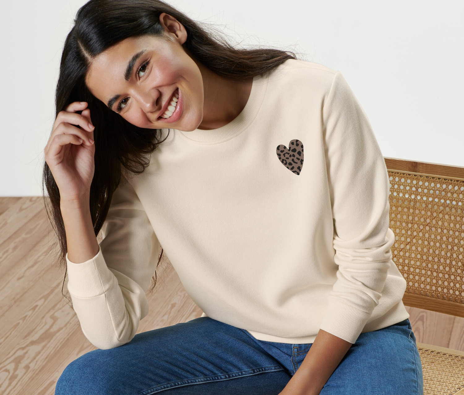 Frau sitzt auf einem Stuhl und trägt ein Sweatshirt mit Print.