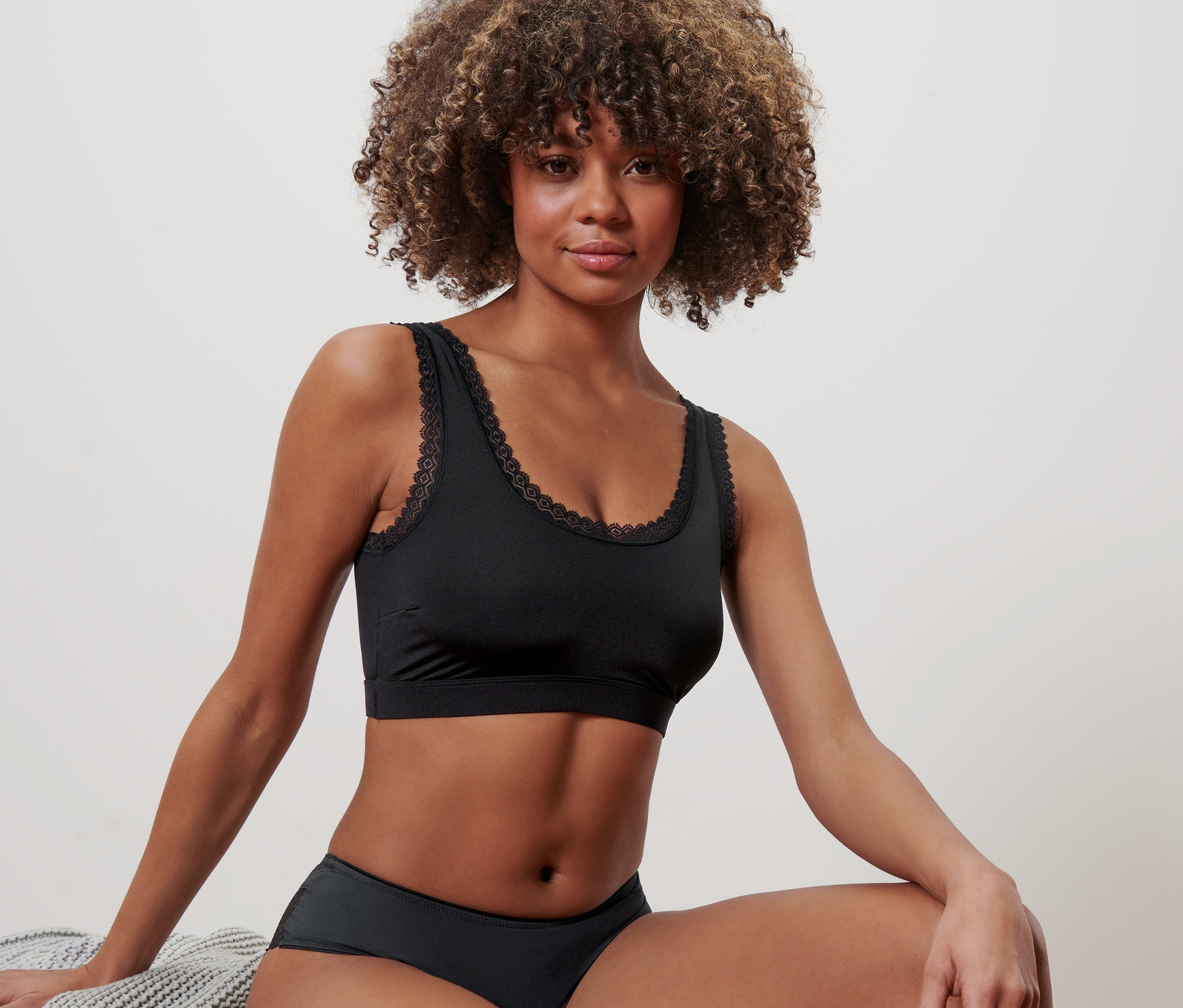 Frau sitzt und trägt ein schwarzes Bustier.