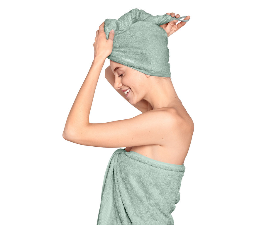 Eine Frau legt ein hellblaues Turban-Handtuch um ihren Kopf.