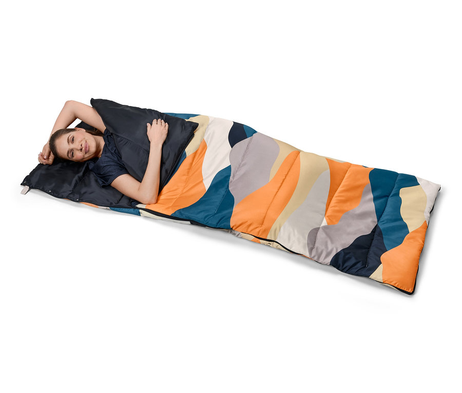 Frau liegt in einem 4-in-1-Decken-Schlafsack mit farbigem Muster.