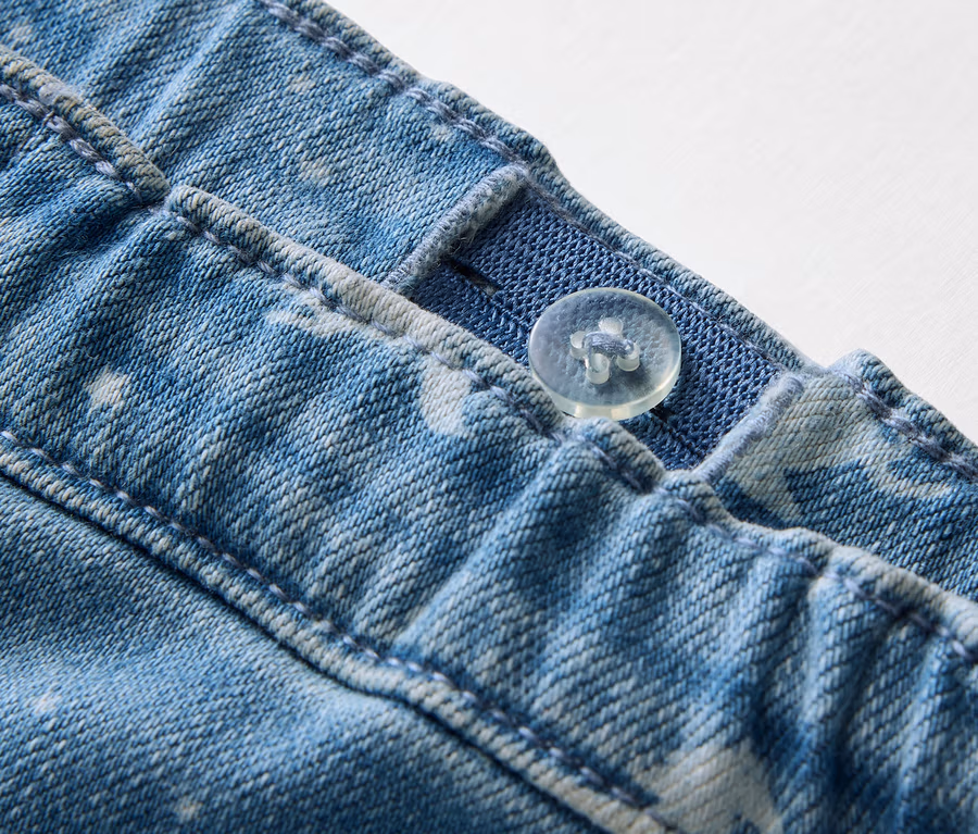 Detailaufnahme von Kinder-Treggings mit Knopf und verstellbarem Gummibund.