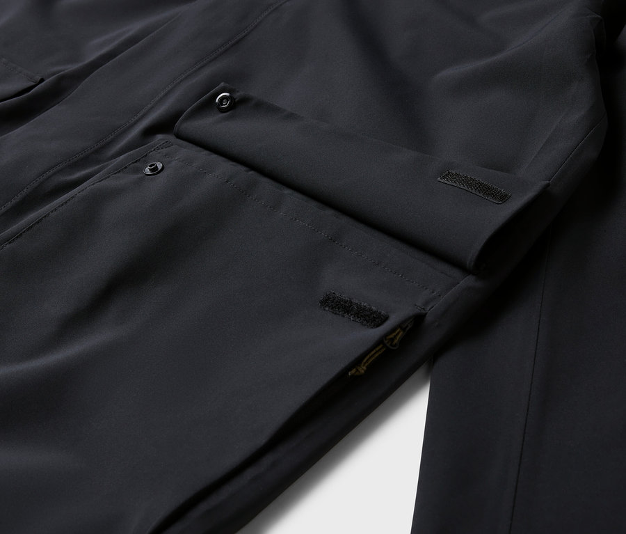 Detailaufnahme einer schwarzen Jacke mit Taschen und Knöpfen.