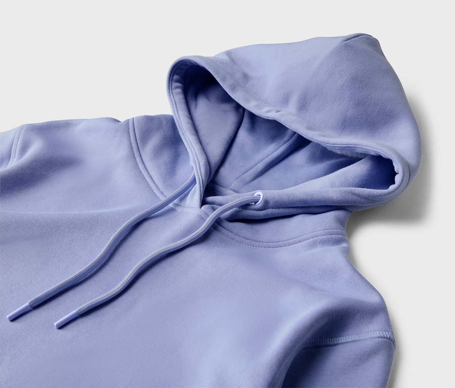 Detailansicht eines hellvioletten Kapuzenpullovers mit Kordelzug auf hellem Hintergrund.