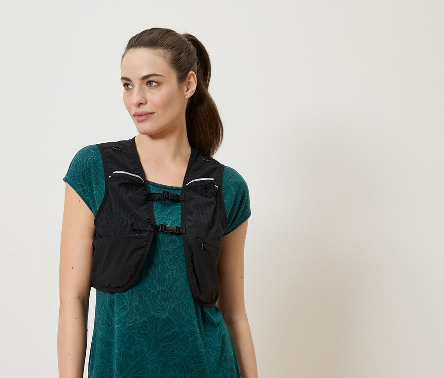 Frau trägt eine schwarze Laufweste über einem grünen Kleid.