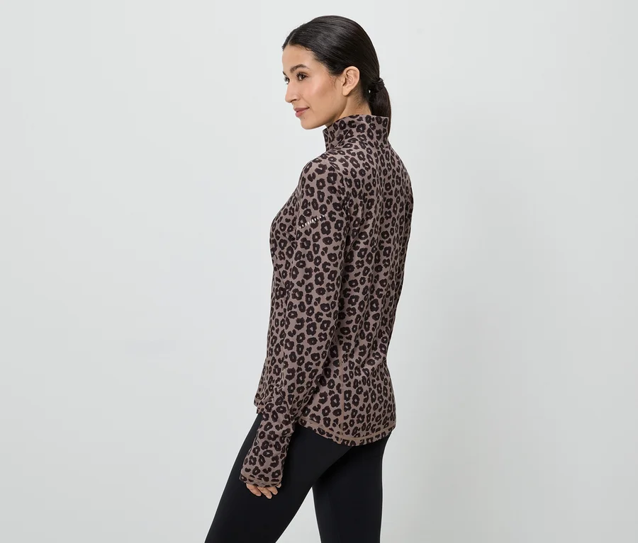 Frau im braunen, langärmeligen Leopardenmuster-Oberteil und schwarzen Leggings, seitliche Ansicht.