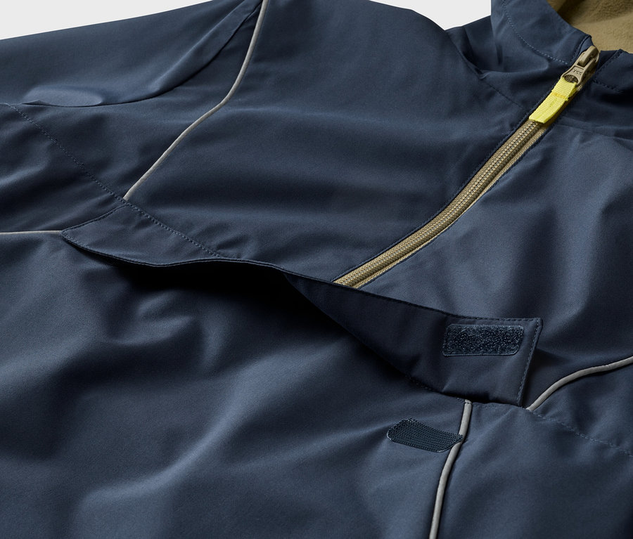 Nahaufnahme einer marineblauen Jacke mit gelbem Reißverschluss und Klettverschluss.