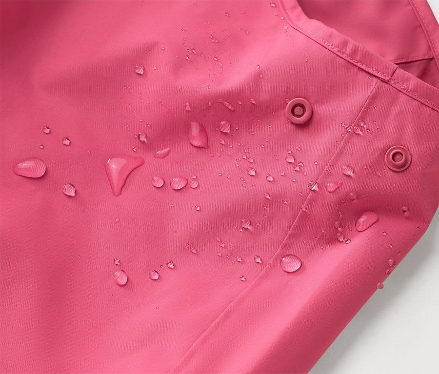 Nahaufnahme einer pinkfarbenen Jacke mit Wassertropfen und zwei Druckknöpfen.
