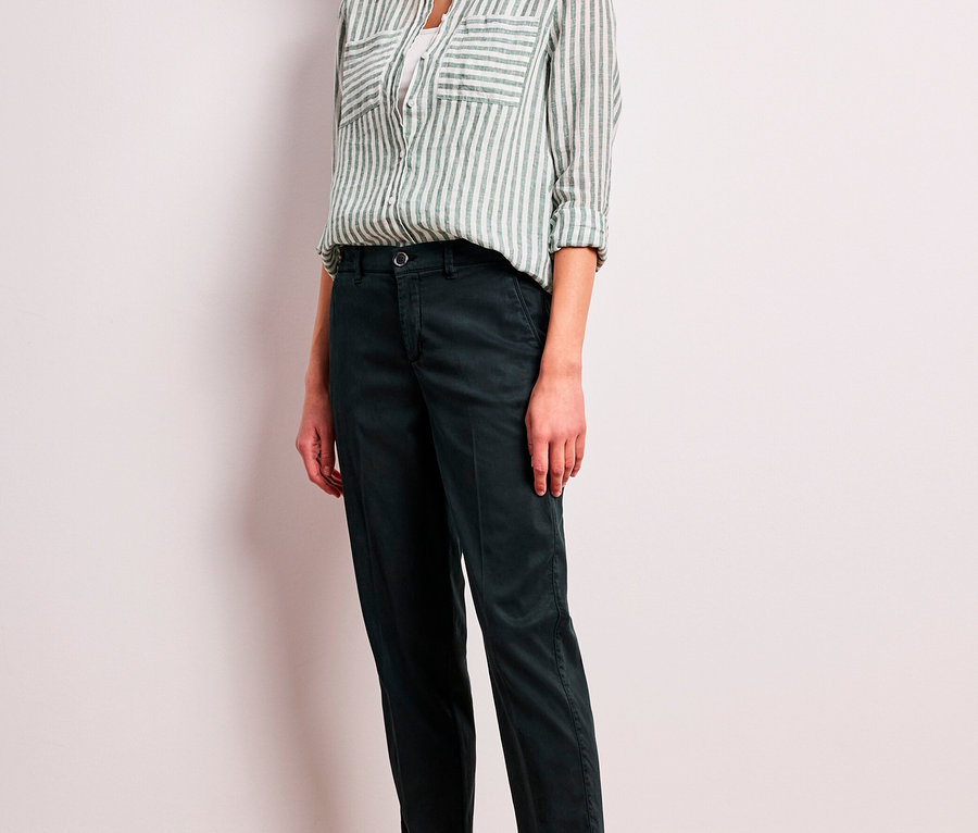 Frau trägt eine grün-weiß gestreifte Street One Hemdbluse, dunkle Cropped-Hose und helle Sneaker.