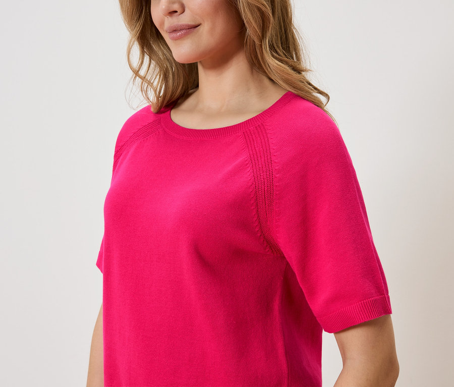 Frau trägt einen pinkfarbenen Pullover mit kurzen Ärmeln.