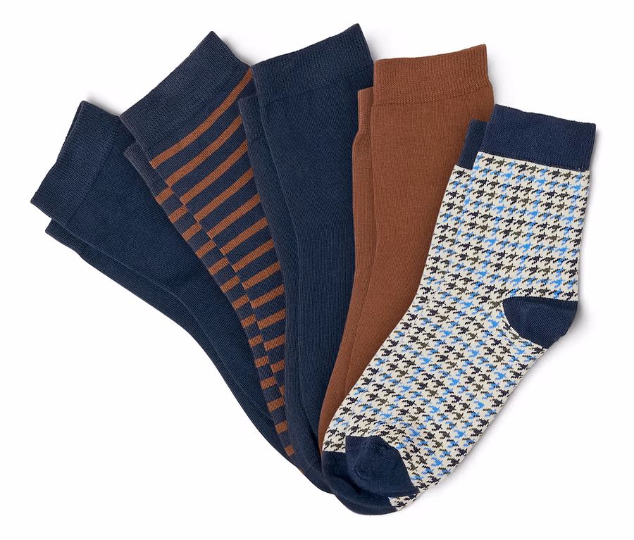 Fünf Paar Socken, darunter zwei einfarbige marineblaue, eine marineblaue mit braunen Streifen, eine einfarbige braune und eine weiße mit blauem Hahnentrittmuster.