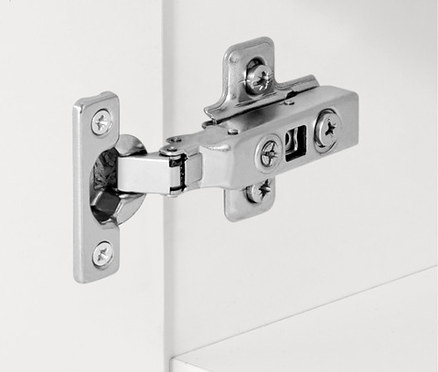 Detail eines silbernen Scharniers an einem weißen Schrank.