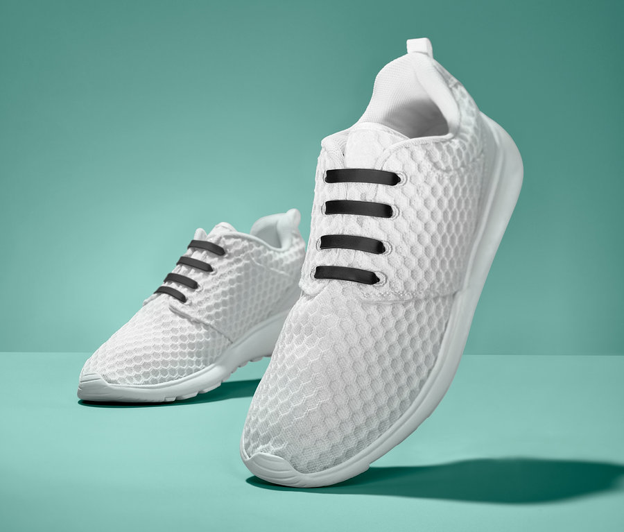 Zwei weiße Turnschuhe mit schwarzen elastischen Silikon-Schnürsenkeln. 20 elastische Silikon-Schnürsenkel.