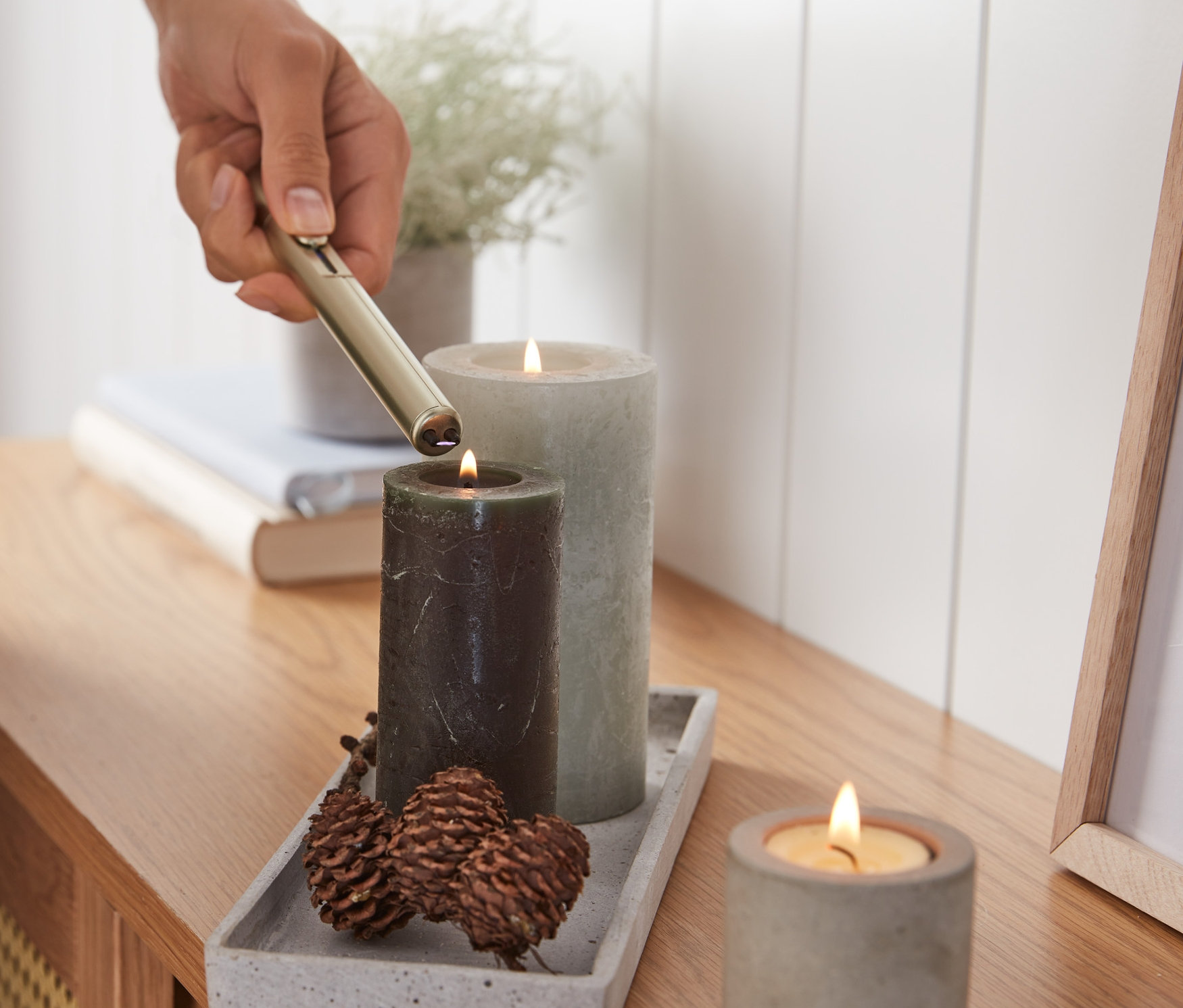 Eine Person zündet eine Kerze mit einem elektrischen Lichtbogen-Feuerzeug an.