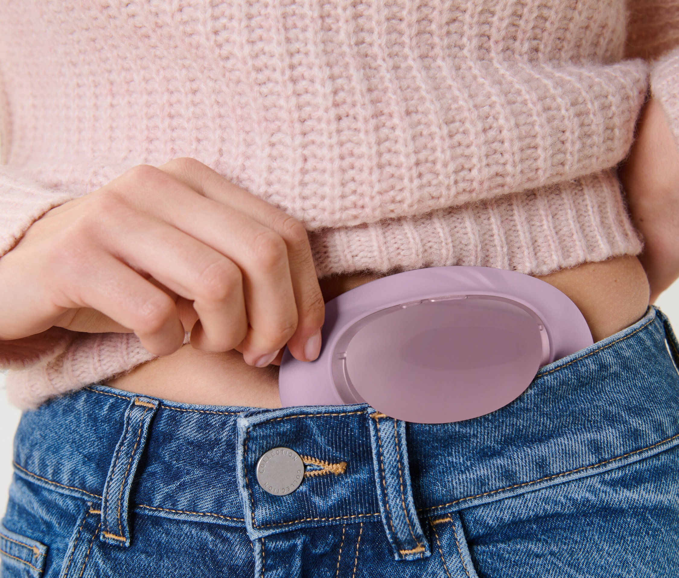Frau steckt Akku-Bauchwärmer in Jeanshosentasche.