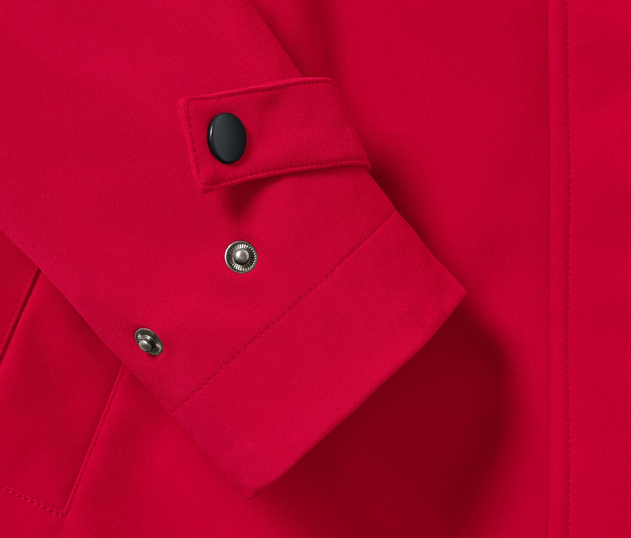 Detailansicht Ärmel eines Softshell-Mantels mit schwarzem Knopf und Druckknöpfen.