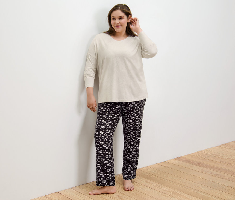 Frau steht mit Pyjama an der Wand.