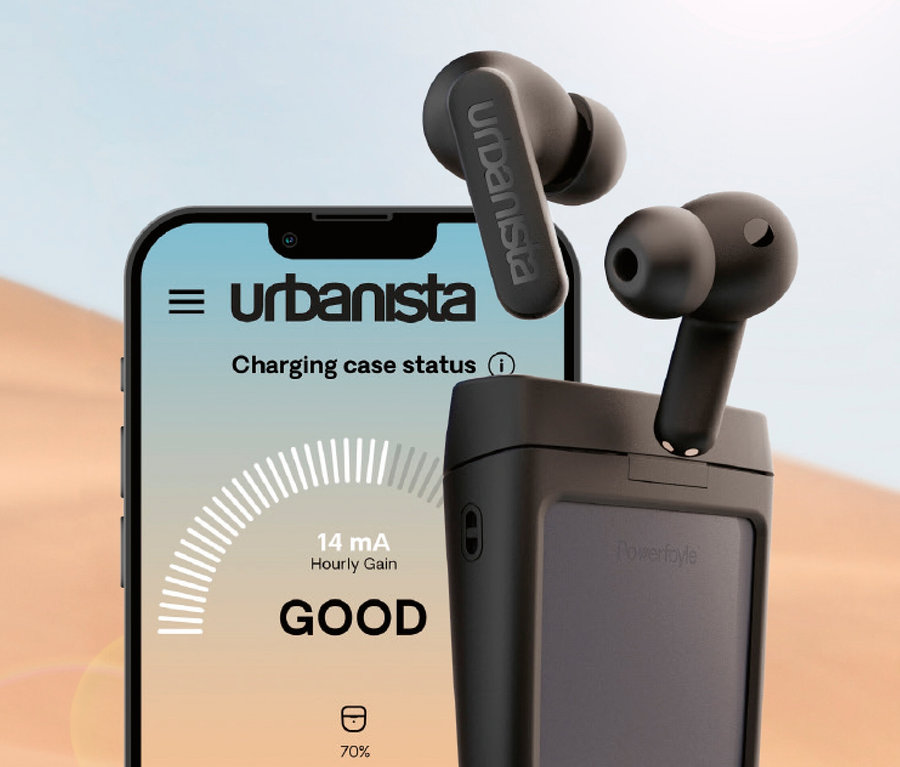 Schwarze In-Ear Kopfhörer mit Solarladefunktion »Urbanista Phoenix« neben einem Smartphone mit Ladeanzeige.