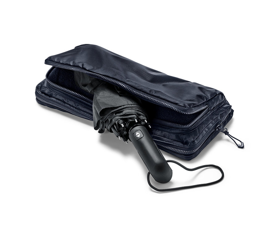 Schwarzer Regenschirm, der teilweise in einem blauen 2-in-1-Shopper-und-Rucksack steckt.