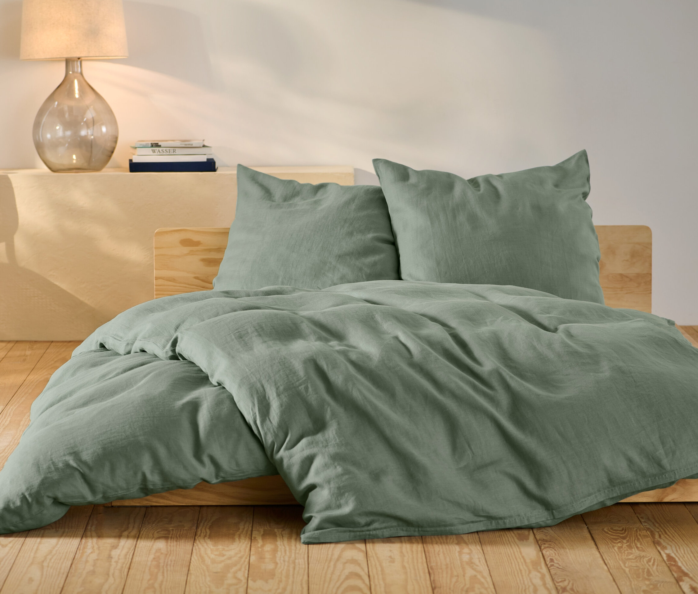 Grüne Leinen-Bettwäsche in Normalgröße und Übergröße auf einem Bett.