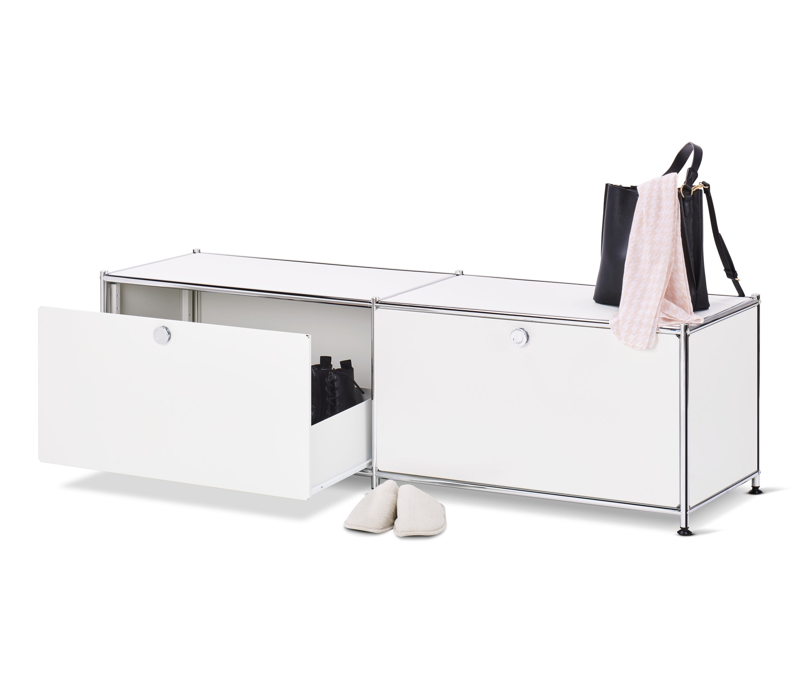 Ein geöffnetes, weißes Lowboard Metall »CN3« mit Schubladen und Schuhen darin, daneben ein Paar cremefarbene Hausschuhe, oben auf dem Schrank eine schwarze Handtasche und ein rosa Schal.