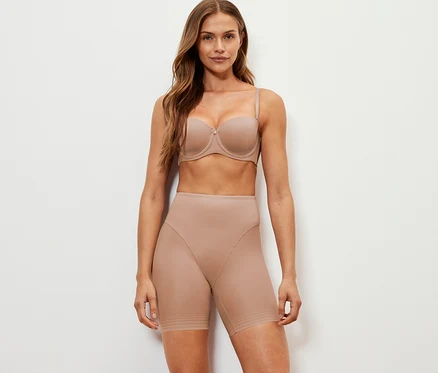 Frau posiert in beigem BH und Shaping-Shorts.