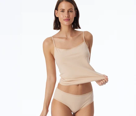 Frau hält ein beiges Tanktop und trägt einen 2 SCHIESSER Hipster, sand.