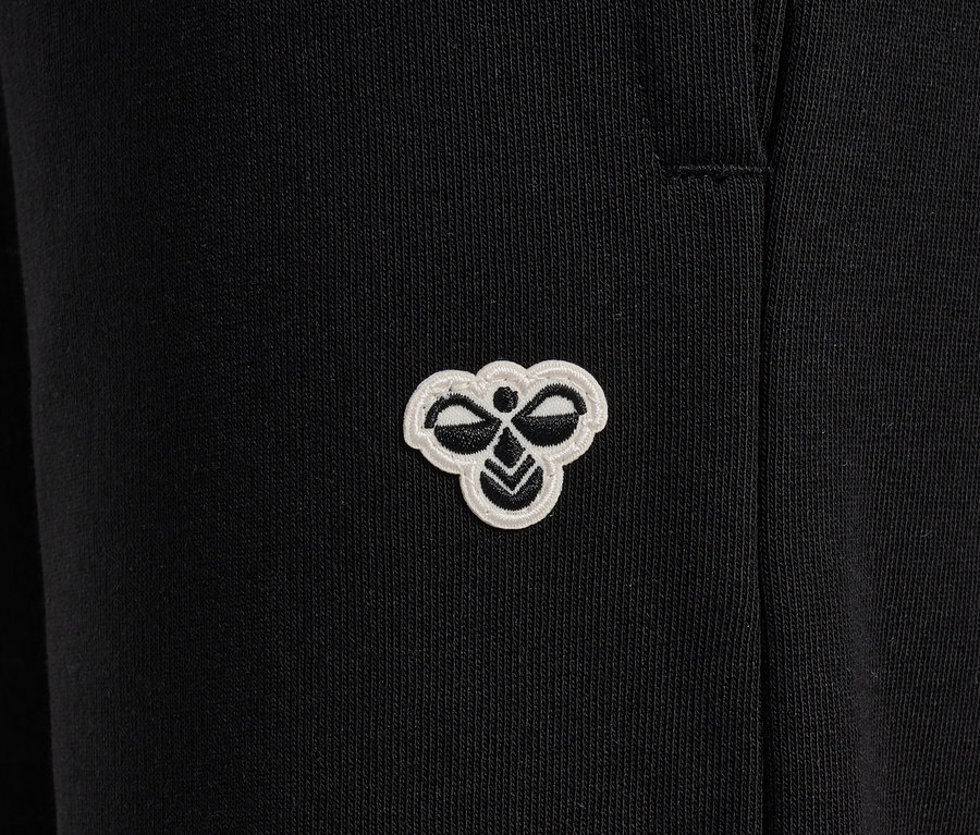 Detailaufnahme einer schwarzen HUMMEL HMLJR Loose WL Trainingshose mit Logo.