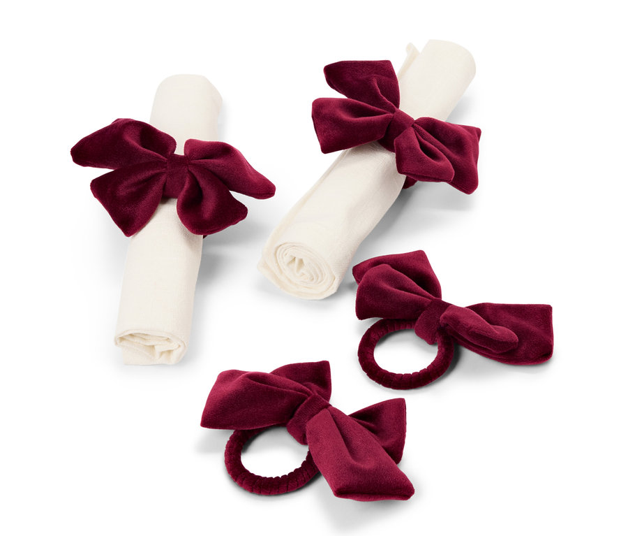 Zwei Servietten, die mit burgunderroten Samtschleifen gebunden sind, und zwei einzelne Serviettenringe mit burgunderroten Schleifen.
