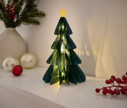 Dekorativer Papierweihnachtsbaum mit Stern auf einem weißen Regal.