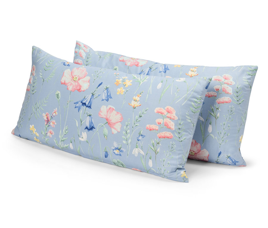 Zwei Kissen mit Blumenmuster auf blauem Grund liegen übereinander.