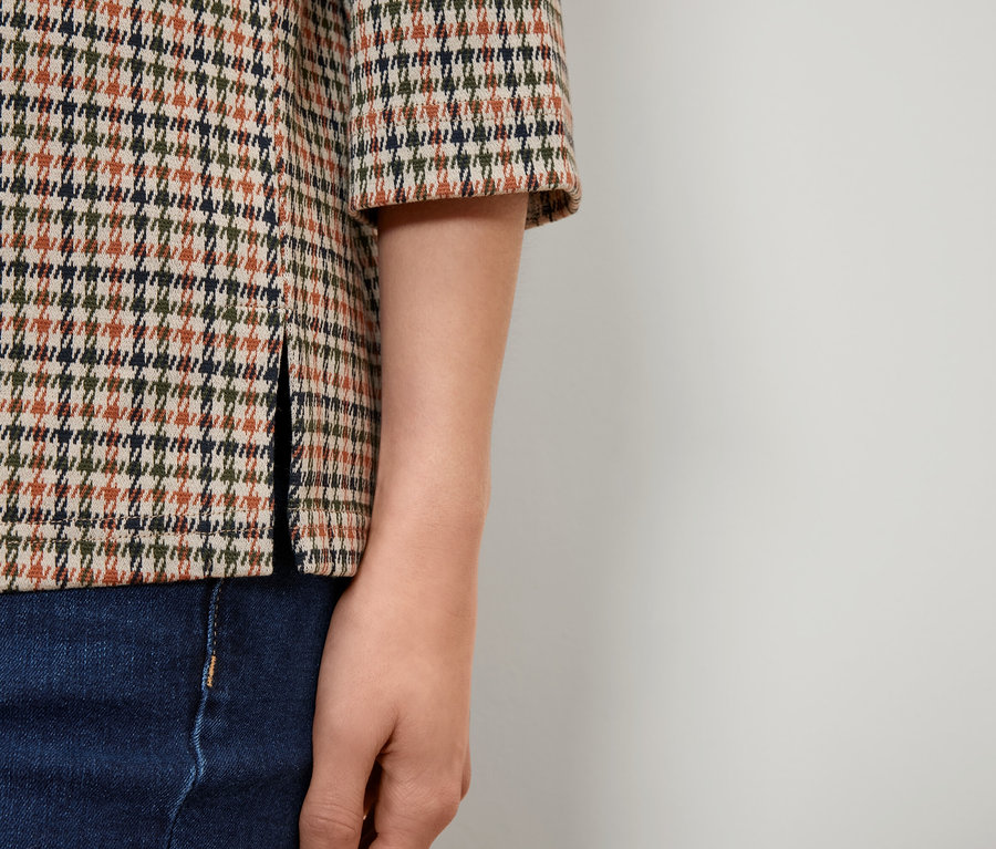 Detailaufnahme einer Damenbluse mit Hahnentrittmuster und Jeans.