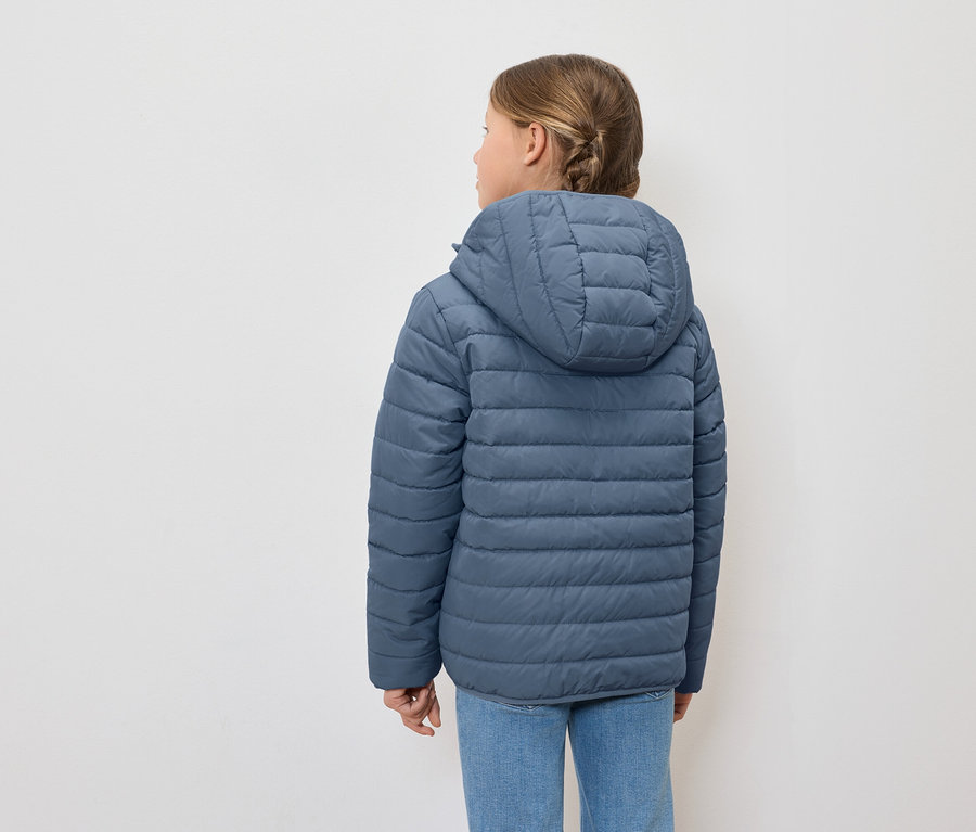 Mädchen von hinten, trägt eine blaue Daunenjacke mit Kapuze und blaue Jeans.