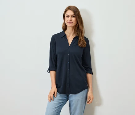 Frau trägt ein marineblaues Langarmhemd und Jeans.