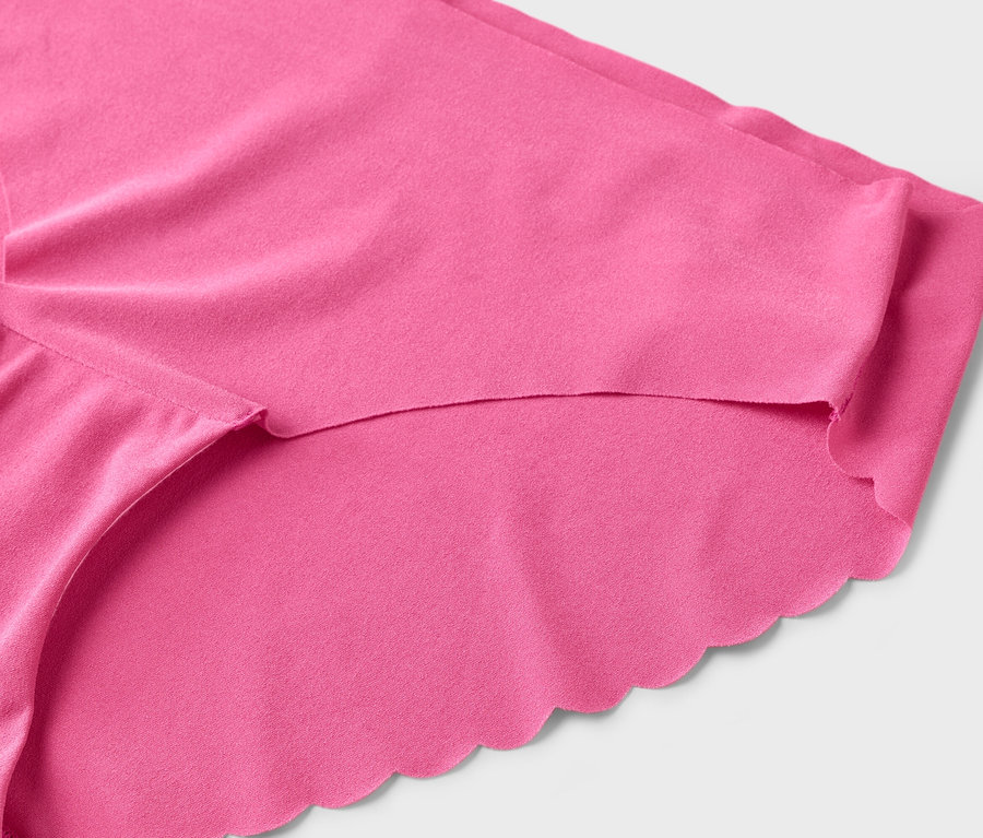 Nahaufnahme eines pinkfarbenen Slips mit gewelltem Rand vor einem weißen Hintergrund.